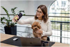 Porträt von Mitarbeiterin die ein Selfie mit ihrem Hund macht