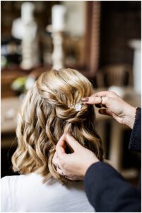 Braut wird von ihrer Stylistin gestylt, die eine Haarspange ins Haar steckt