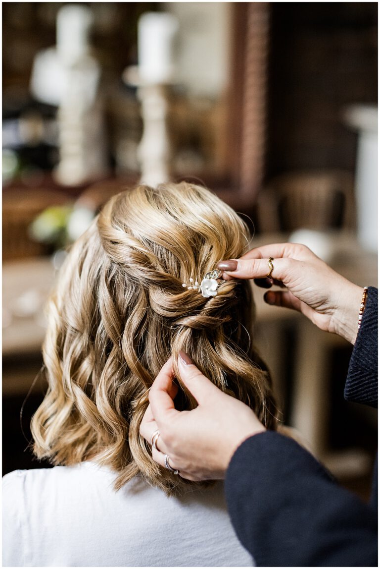 Braut wird von ihrer Stylistin gestylt, die eine Haarspange ins Haar steckt