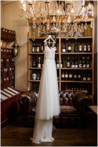 Brautkleid hängt am Kronleuchter im La Dü vor einem Weinregal