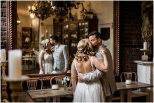 Brautpaar küsst sich auf ihrer Hochzeit vor einem großen Spiegel iim La Dü