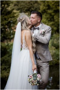 Junges Brautpaar mit Brautstrauß küsst sich