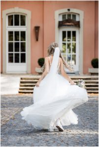 Junge Braut mit Sneakers tanzt in ihrem Brautkleid und dreht sich damit