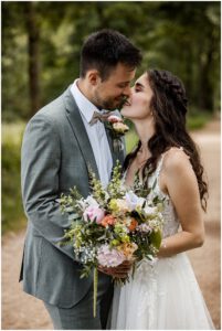 Brautpaar küsst sich und hält einen Brautstrauß